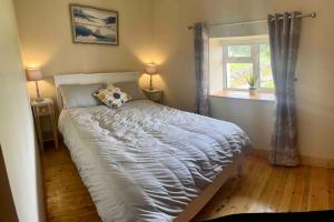 sypialnia z dużym łóżkiem i oknem w obiekcie Tigh Seoighe - Renovated Cottage Tourmakeady w mieście Toormakeady
