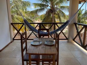 a table with two chairs and a hammock on a balcony at BEACH HOUSE - Apartment 2 - com cozinha - with kitchen in Barra Grande