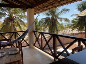 a porch with a hammock and palm trees and a table at BEACH HOUSE - Apartment 2 - com cozinha - with kitchen in Barra Grande