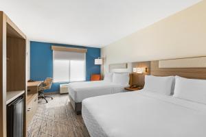 ein Hotelzimmer mit 2 Betten und einem Schreibtisch in der Unterkunft Holiday Inn Express Belgrade-Bozeman Area, an IHG Hotel in Belgrade
