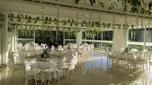 a banquet hall with white tables and chairs and plants at Hotel Palmeras De Luz in Moniquirá +84 photos