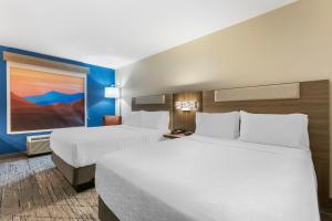 a hotel room with two beds and a painting on the wall at Holiday Inn Express Belgrade-Bozeman Area, an IHG Hotel in Belgrade