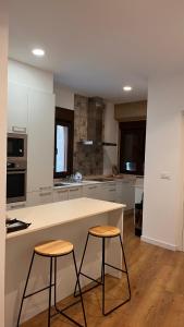 a kitchen with a white counter and two stools at A de Juan - Tres Marias Apartments in Redondela