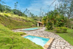 ein Schwimmbad inmitten eines grasbewachsenen Hügels in der Unterkunft Refúgio Familiar-Casa de Campo em Gravata-3QTS-065 in Gravatá