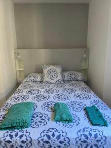 Una cama con dos almohadas verdes encima. en A de Juan - Tres Marias Apartments, en Redondela
