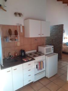 a kitchen with a white stove and a microwave at CABAÑAS LOS OLIVOS in Las Grutas