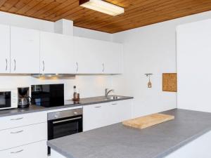 Frøstrupにある7 person holiday home in Fr strupの白いキャビネットと木製の天井が備わるキッチン