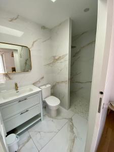 Baño blanco con lavabo y aseo en Chambre Privée Accès Piscine, en Mimizan