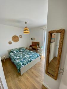 1 dormitorio con cama y espejo en Chambre Privée Accès Piscine, en Mimizan