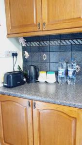 a kitchen counter top with cups and water bottles at offering cheerfull and spacious rooms throught this 3 bed room semi detached house with large garden and off-street parking. in Addington