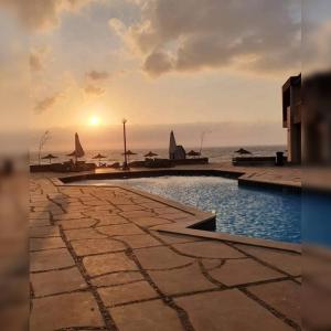 a swimming pool with the ocean in the background at شاليه بقرية كورونادو مارينا - Coronado Marina عائلات فقط in Ain Sokhna