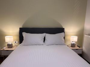 a bed with white pillows and two lamps on tables at Casa Calma II by Immobilis in Ária +25 photos