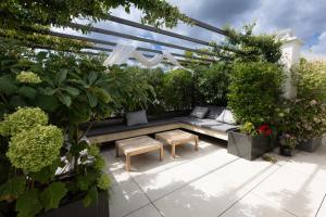 a garden with a couch and tables and plants at Splendid apartment and rooftop overlooking Paris - Neuilly - Welkeys in Neuilly-sur-Seine
