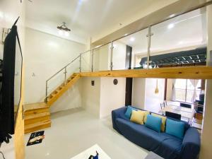 a living room with a blue couch and a staircase at Evergreen Suites Baguio Condo Home Loft in Baguio
