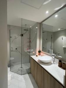布塞里亞斯的住宿－Marítima Golf Luxury Department 2BR，一间带两个水槽和玻璃淋浴间的浴室