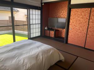 a bedroom with a bed and a flat screen tv at 貸切古民家Yukan in Sengokuhara