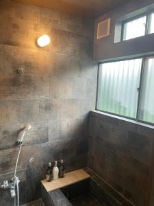 a bathroom with a shower with a bench and a window at 貸切古民家Yukan in Sengokuhara
