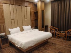 um quarto com uma grande cama branca e uma cadeira em Pinnacle Vesta Homestay em Mussoorie