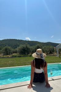 a woman in a hat sitting next to a swimming pool at Astrum Luxury Suites in Vourvourou