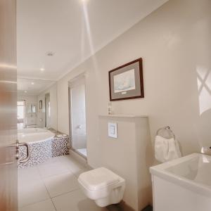 a white bathroom with a tub and a toilet and a sink at Sunset Villa in Langebaan +50 photos