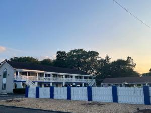 a white house with a blue fence in front of it at Point Pleasant Inn in Point Pleasant Beach