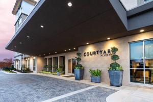 阿爾法利塔的住宿－Courtyard by Marriott Atlanta Alpharetta/Avalon Area，一座种植盆栽植物的建筑的前方