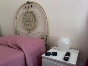 een bed met een paarse sprei en een tafel met afstandsbediening bij Laura Domus in Portici