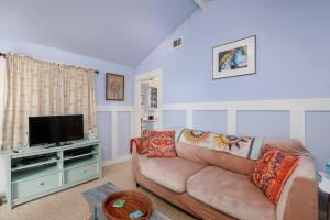 uma sala de estar com um sofá e uma televisão de ecrã plano em The Cottage Guest House em Paso Robles
