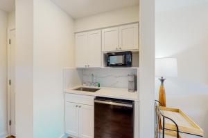 a kitchen with white cabinets and a sink and a microwave at Luau, Unit 6108 in Destin