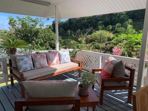 eine Veranda mit einem Sofa, 2 Stühlen und einem Sonnenschirm in der Unterkunft Fare Manatea 19 in Papeete