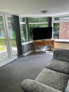 a living room with a flat screen tv and a desk at The Village apartment. in Marton