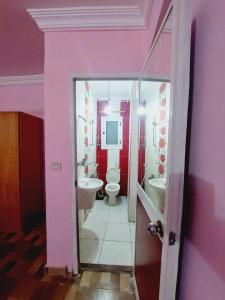 une salle de bains rose avec deux lavabos et des toilettes. dans l'établissement شقة مفروشة مجهزة بشارع خالد بن الوليد بالإسكندرية مصر, à Alexandrie