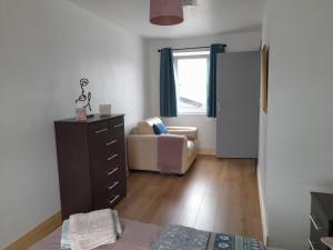 a bedroom with a dresser and a chair and a window at Central Town Apartment in Wexford