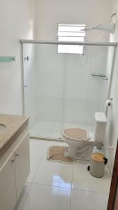 La salle de bains est pourvue de toilettes et d'une douche en verre. dans l'établissement Casa da Fé, à Cachoeira Paulista