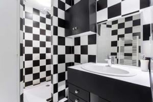 a bathroom with a sink and a black and white checkered wall at Calm in the city center of Lyon in Lyon