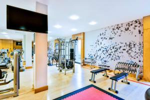einen Fitnessraum mit mehreren Laufbändern und einem Flachbild-TV in der Unterkunft Sheraton Skyline Hotel London Heathrow in Hillingdon