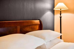 uma cama com uma cabeceira de madeira e um candeeiro em Sheraton Skyline Hotel London Heathrow em Hillingdon