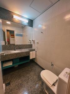 a bathroom with a toilet and a sink and a mirror at BH PARA 2 - HOTEL LUXO Apartamento Particular Savassi in Belo Horizonte