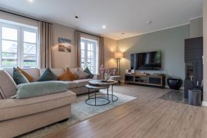 a living room with a couch and a tv at Summer Diek Reetdachhaus Summerdiek 9 in Sankt Peter-Ording