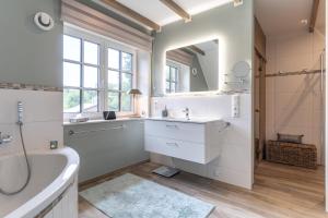 ein Badezimmer mit Badewanne, Waschbecken und Spiegel in der Unterkunft Summer Diek Ferienhaus Summerdiek 7 in Sankt Peter-Ording + 29 Fotos