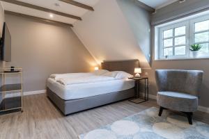 ein Schlafzimmer mit einem Bett und einem Stuhl und einem Fenster in der Unterkunft Summer Diek Ferienhaus Summerdiek 8 in Sankt Peter-Ording