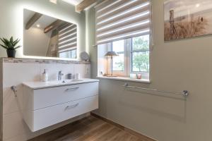 a bathroom with a sink and a mirror at Summer Diek Reetdachhaus Summerdiek 10 in Sankt Peter-Ording +24 photos