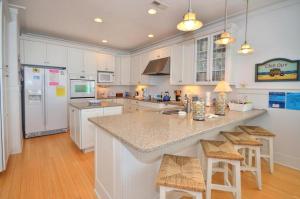 橡树岛Tar Heel Haven的一间厨房,配有白色橱柜和一个带酒吧凳的岛屿