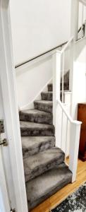 una scala in una casa con pareti bianche e pavimenti in legno di Holiday Apartment a Abbey Wood