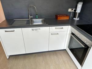 a kitchen with white cabinets and a sink at Traumhafte Haushälfte mit Kamin, Garten & Whirlpool in Berlin