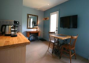 a kitchen with a table and a television on the wall at GÎTE SUR L'ARC EN CIEL in Saint Adrien