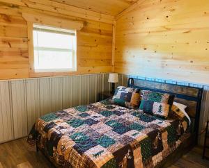 ein Schlafzimmer mit einem Bett in einem Blockhaus in der Unterkunft Brushcreek Falls RV Resort in Princeton