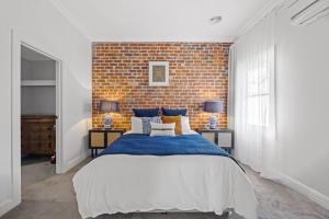 a bedroom with a large bed with a brick wall at Duc De Malakoff in Ballarat