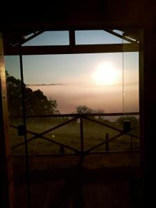 een uitzicht op de zonsondergang door een raam bij Chalet di Alta Montagna in Santo Antônio do Pinhal