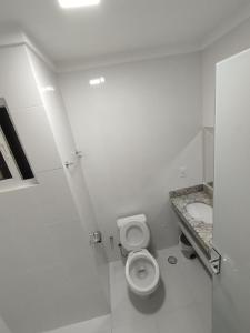 a white bathroom with a toilet and a sink at Caldas Novas Spazzio Diroma com acesso ao Vulcao todos os dias in Caldas Novas